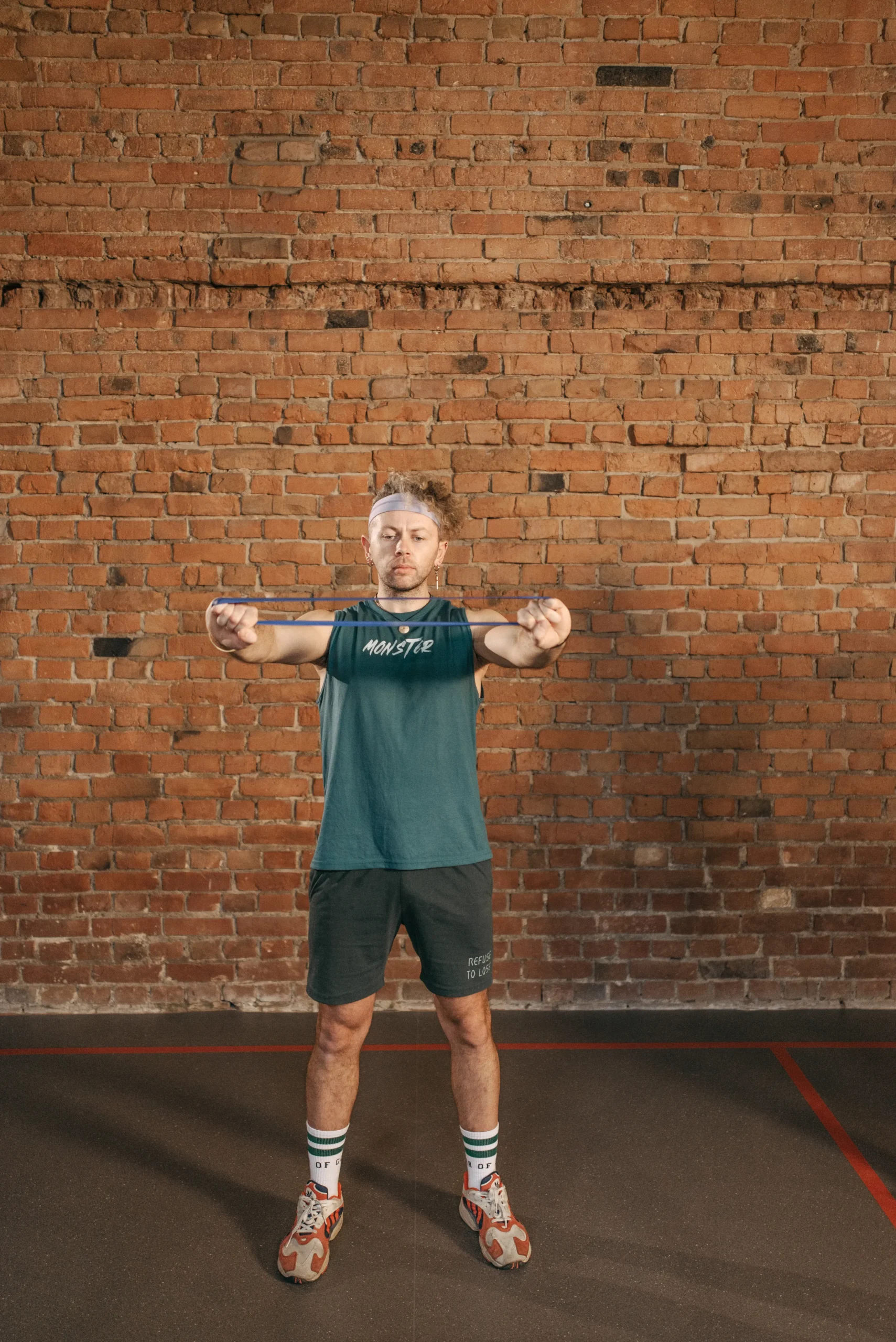 Man training with a resistance band against a brick wall