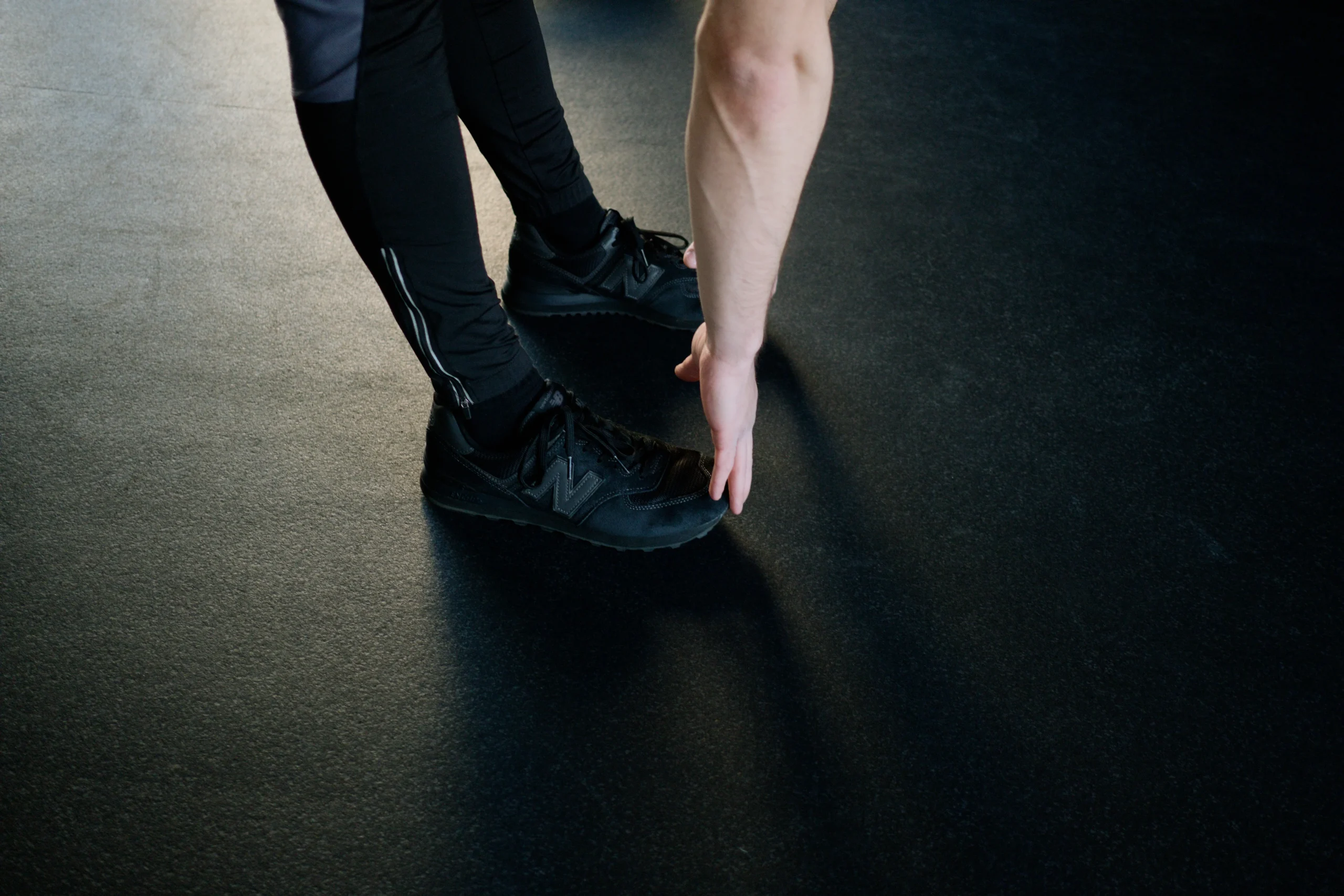 Person stretching down toward the feet on a gym floor