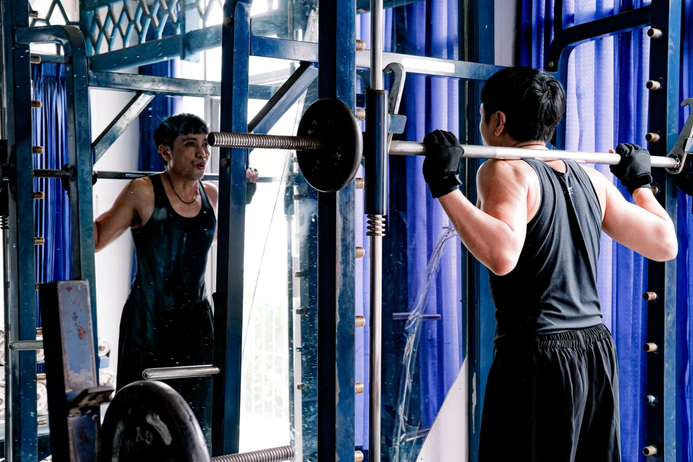 Man performing a barbell squat in a gym