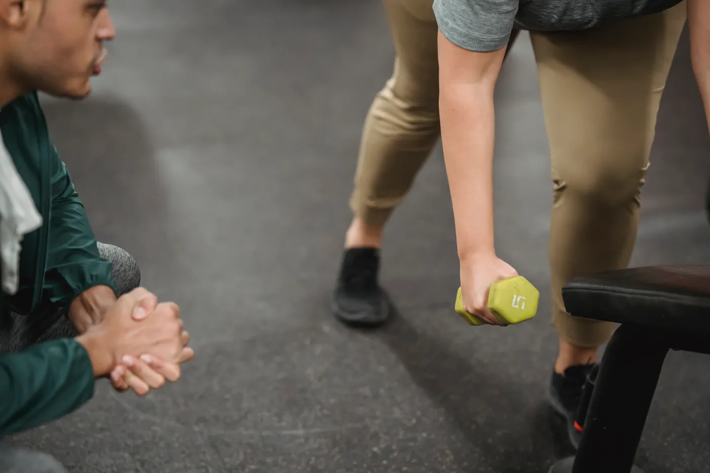 Trainer supervising a woman during a dumbbell workout