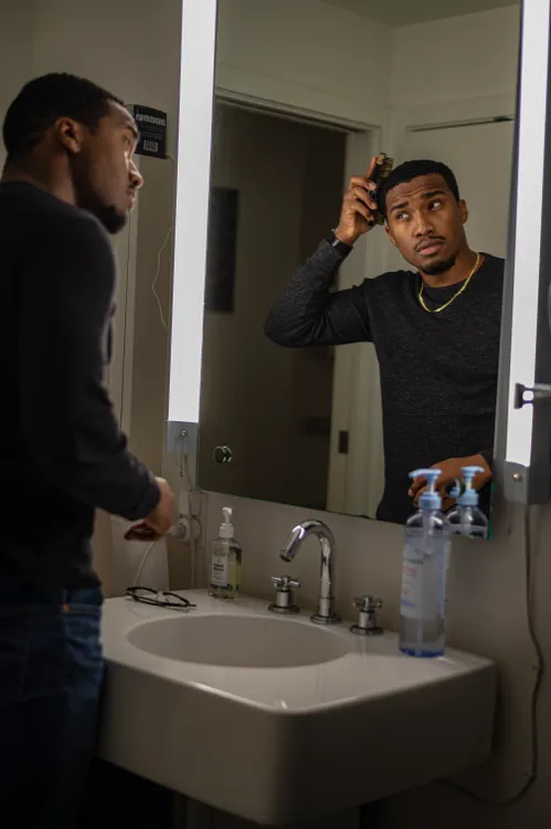 Man brushing his hair while looking in a mirror