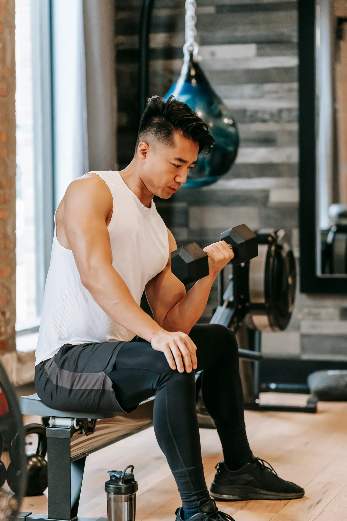 Man performing a controlled seated dumbbell curl in a fitness studio