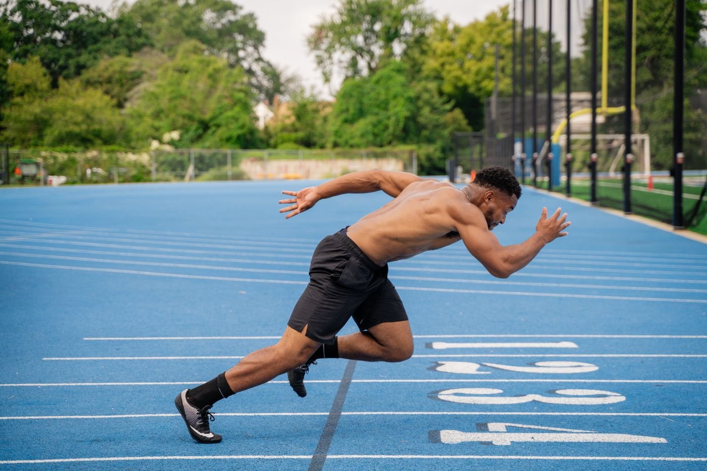 Male runner sprinting on a blue athletics track