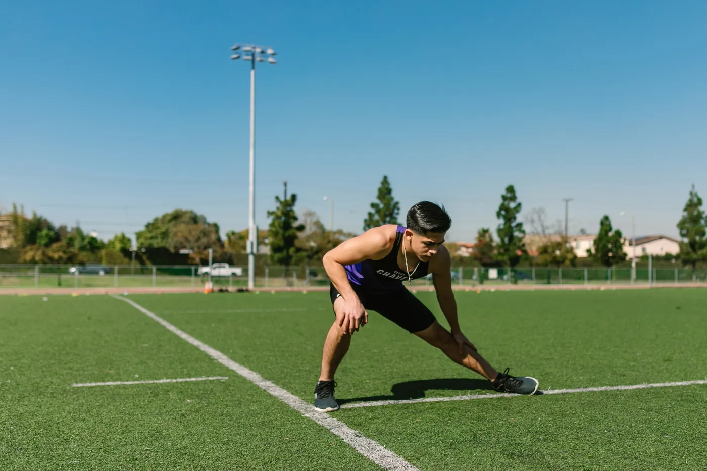 Athlete stretching the inner thighs and legs on a sports field