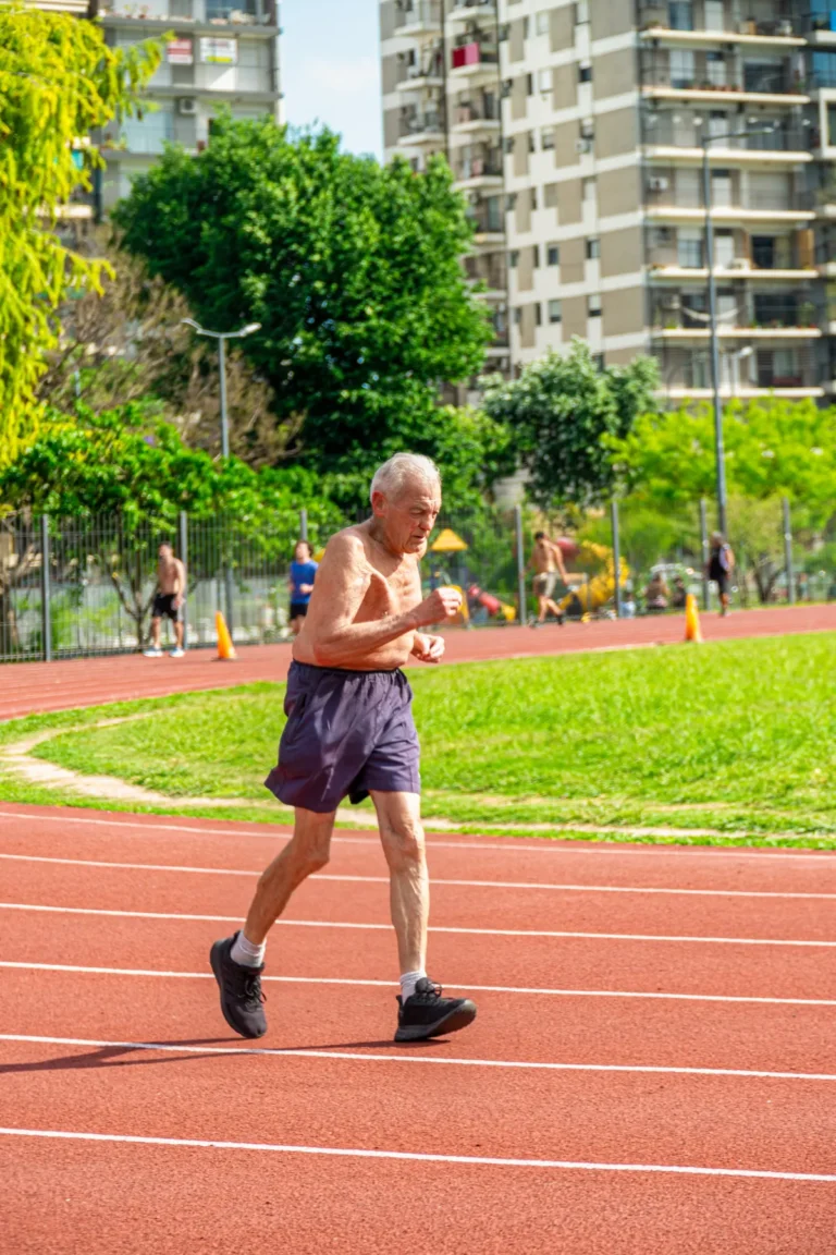 Senior runner jogging on an outdoor track in a sunny park
