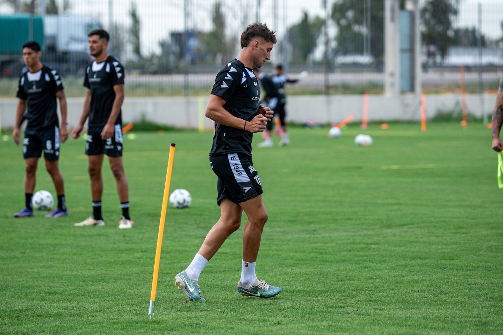 Soccer players running structured drills on a green training field