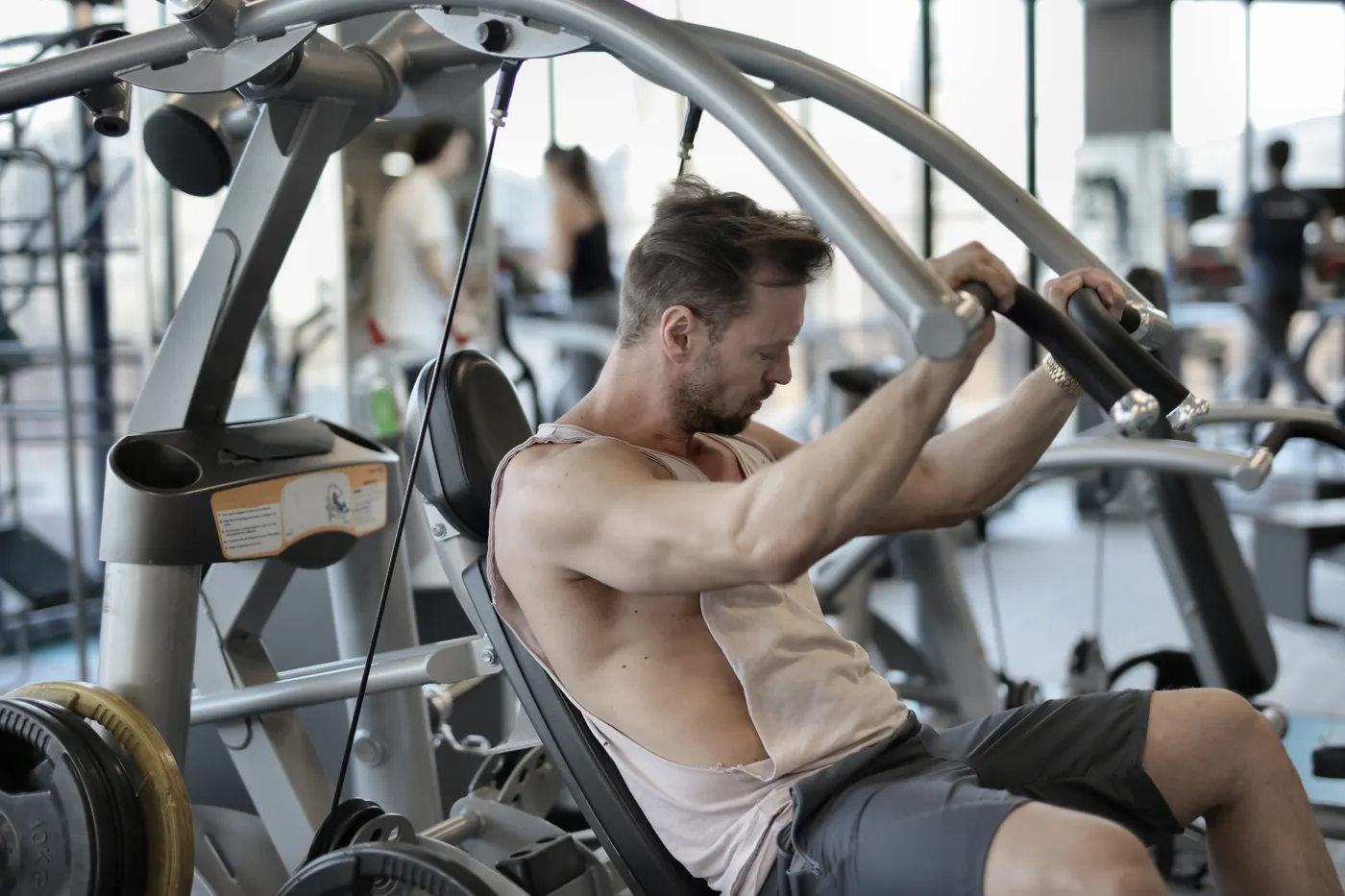 Athlete training with a shoulder press machine in a gym