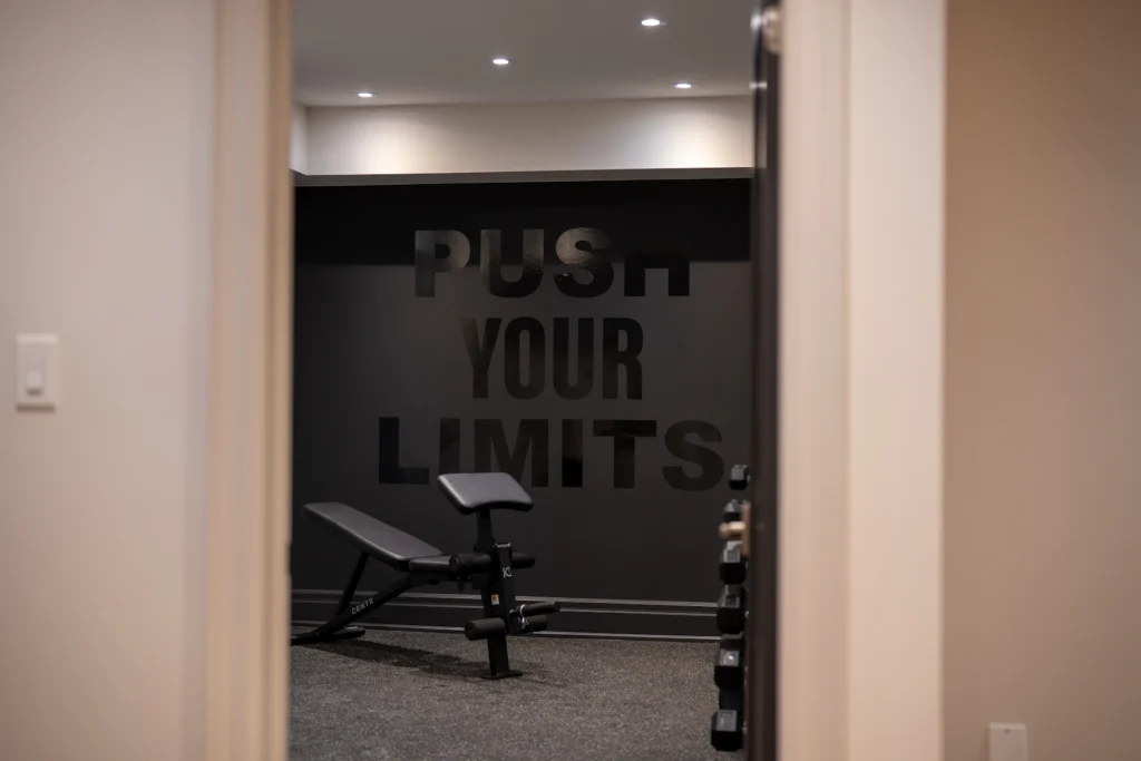 Dark home gym with dumbbells and a motivational wall
