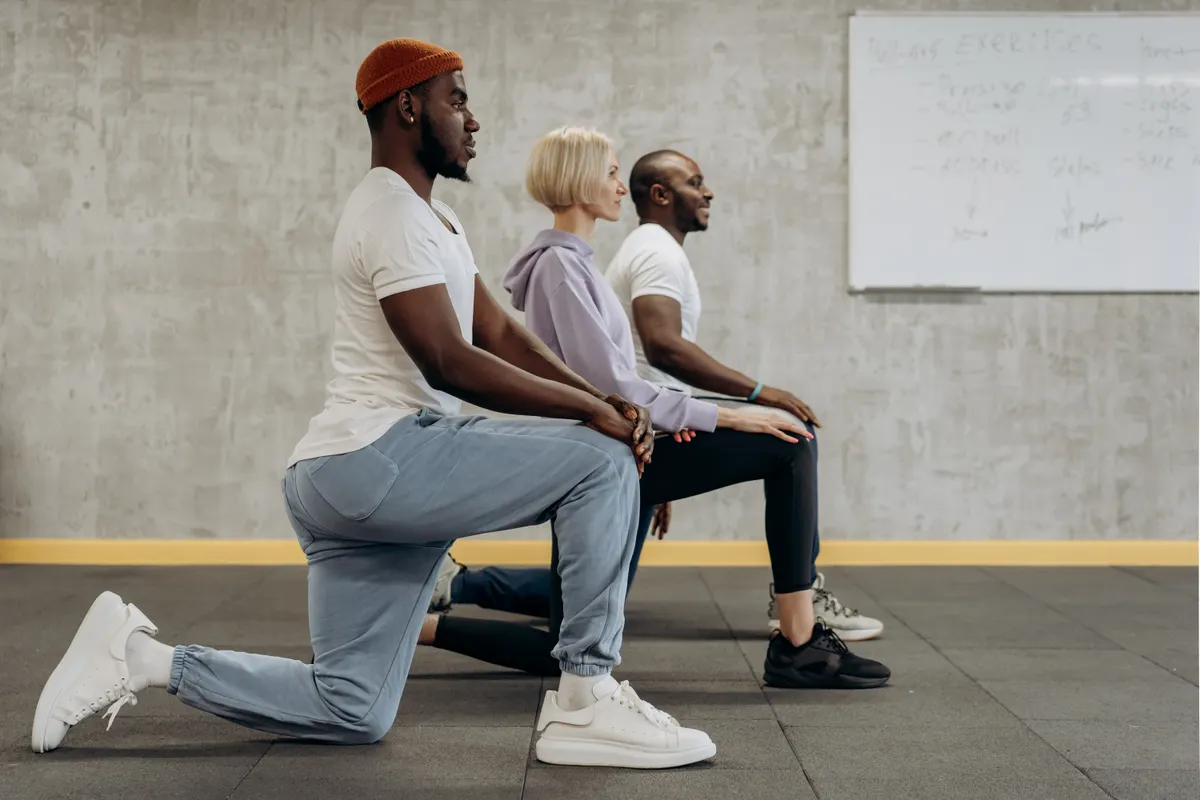 Three exercisers practicing controlled lunges in a studio