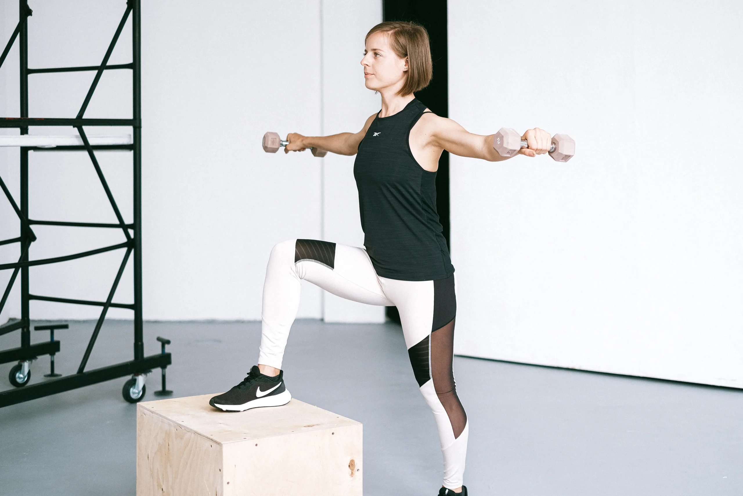 Woman lifting dumbbells with controlled posture in a fitness gym