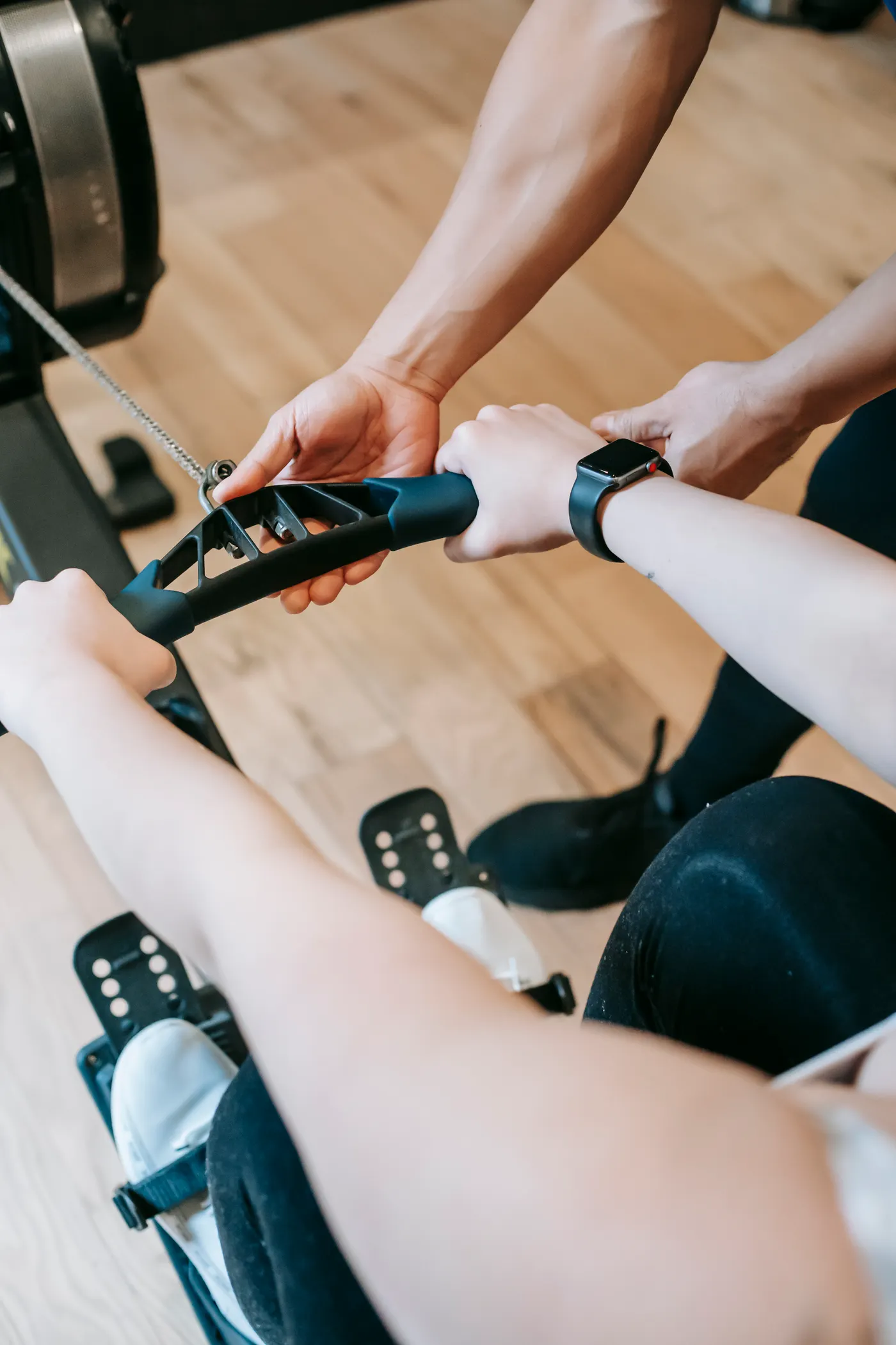 Personal trainer guiding a woman on an indoor rower