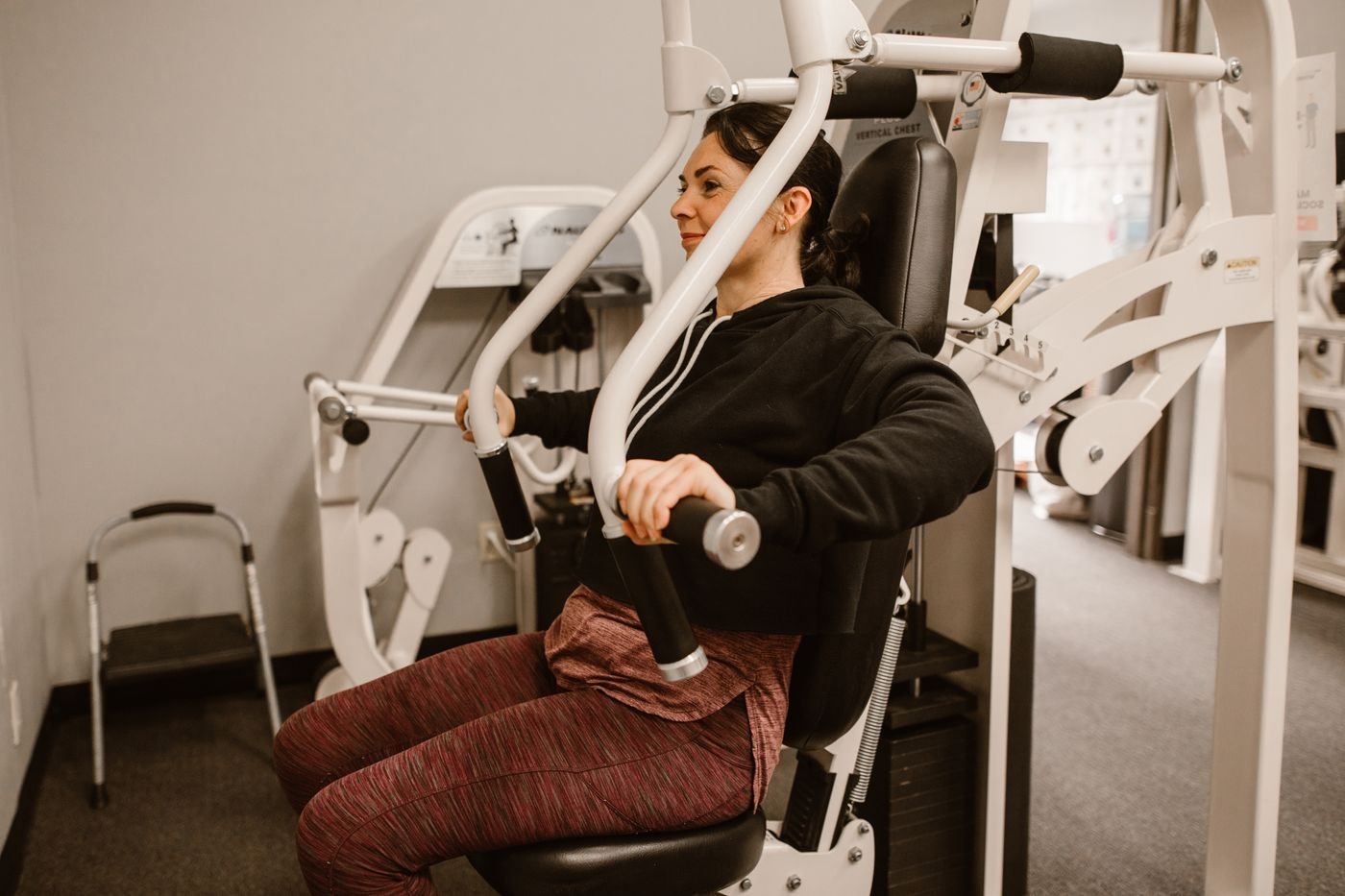 Woman pressing weight on a chest press machine during strength training