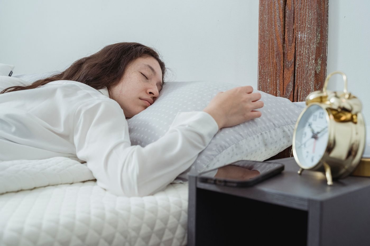 Young woman sleeping near a clock and phone