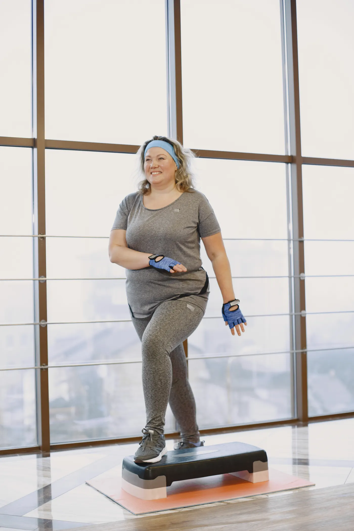 Middle-aged woman performing a step exercise at a gym