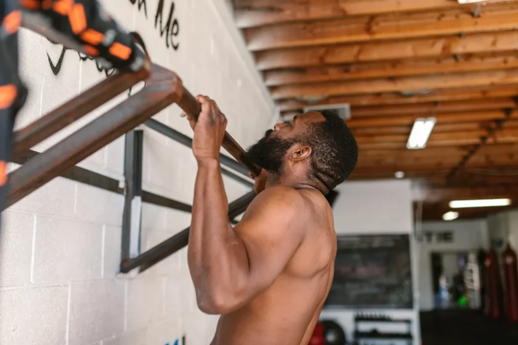 Man performing a pull-up on a fixed bar in a gym