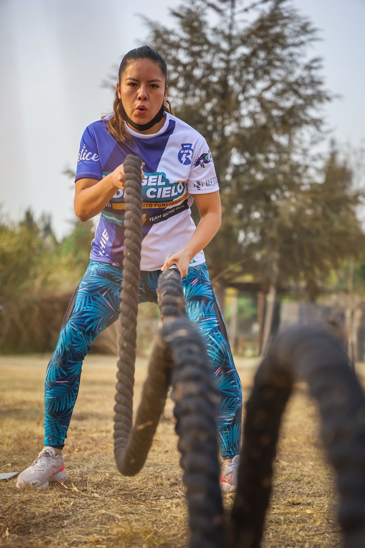 Woman training with battle ropes outdoors in a park