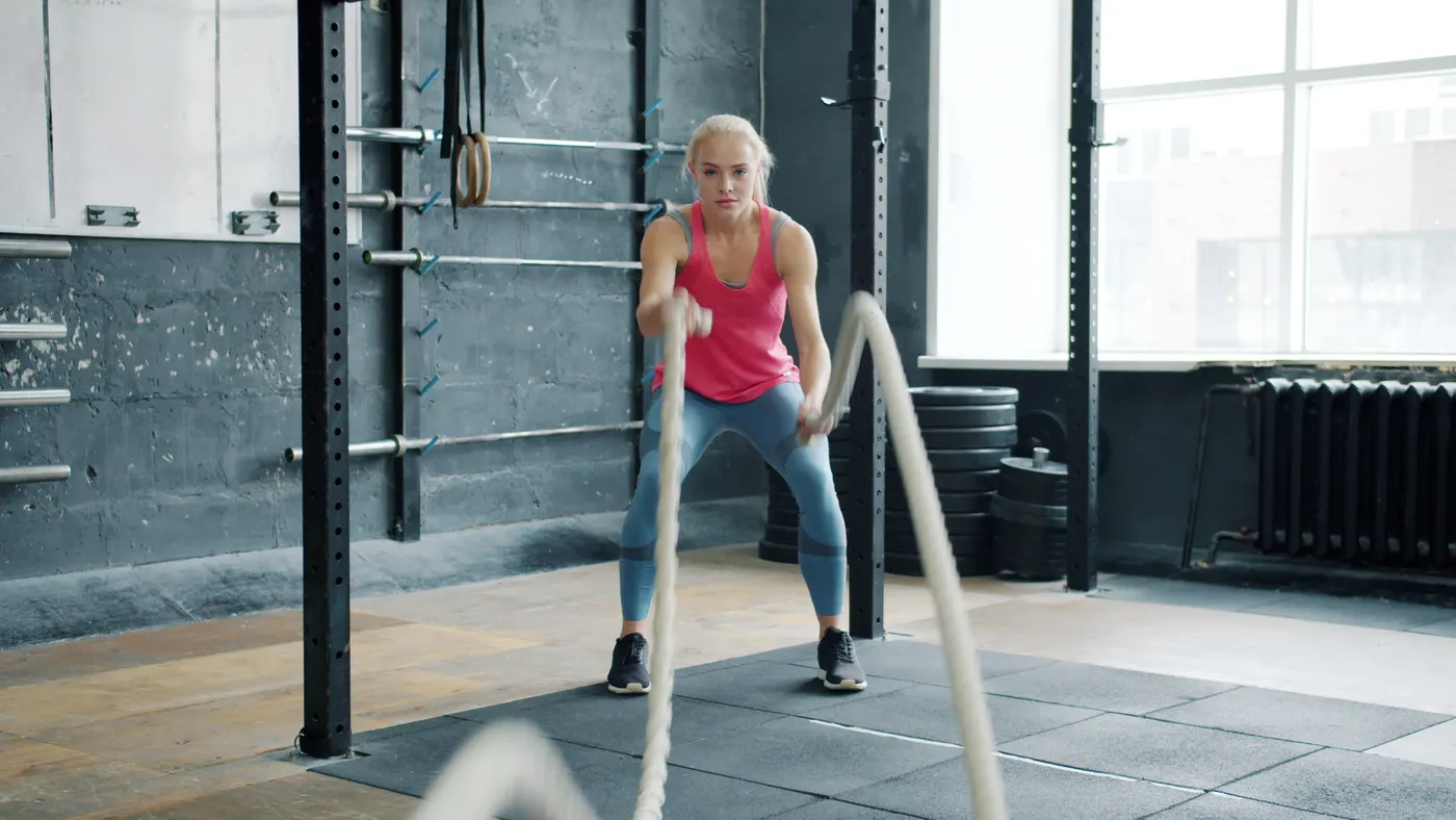 Woman training with battle ropes in a gym