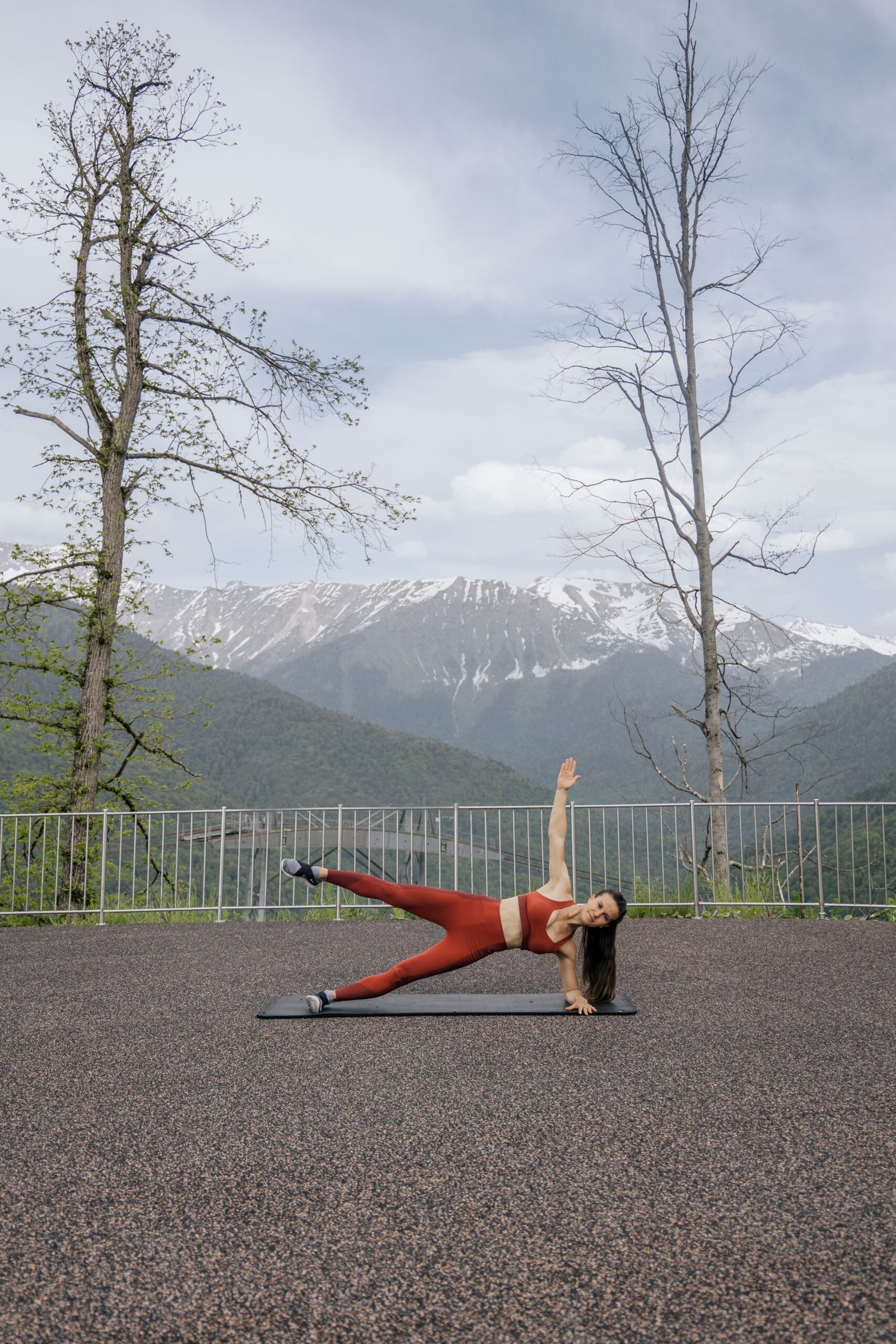 Woman performing a side plank with mountain scenery behind her