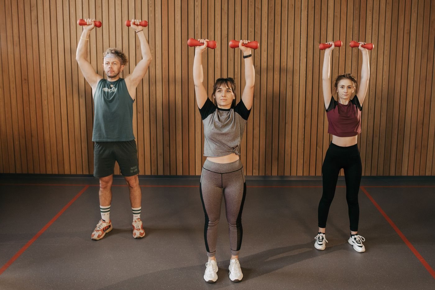 Group performing dumbbell exercises in a gym to build strength