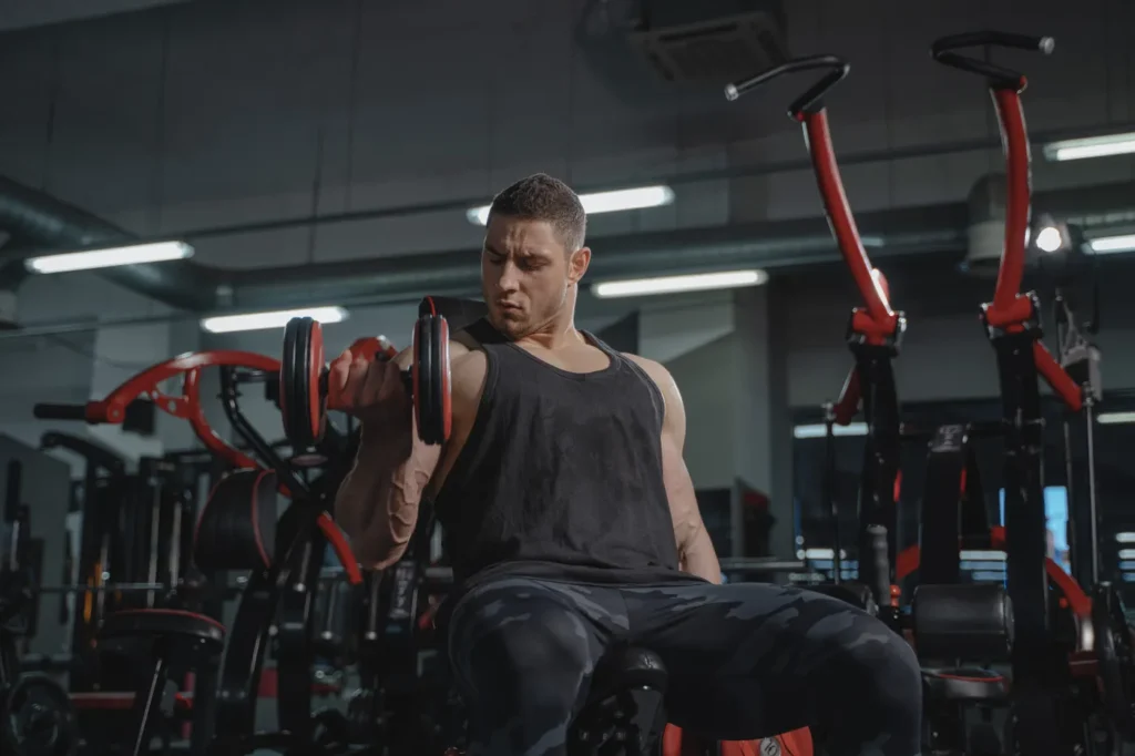 Athlete performing seated dumbbell curls during an upper-body gym session