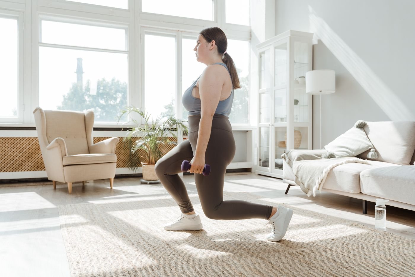 Woman performing a dumbbell lunge to train single-leg strength