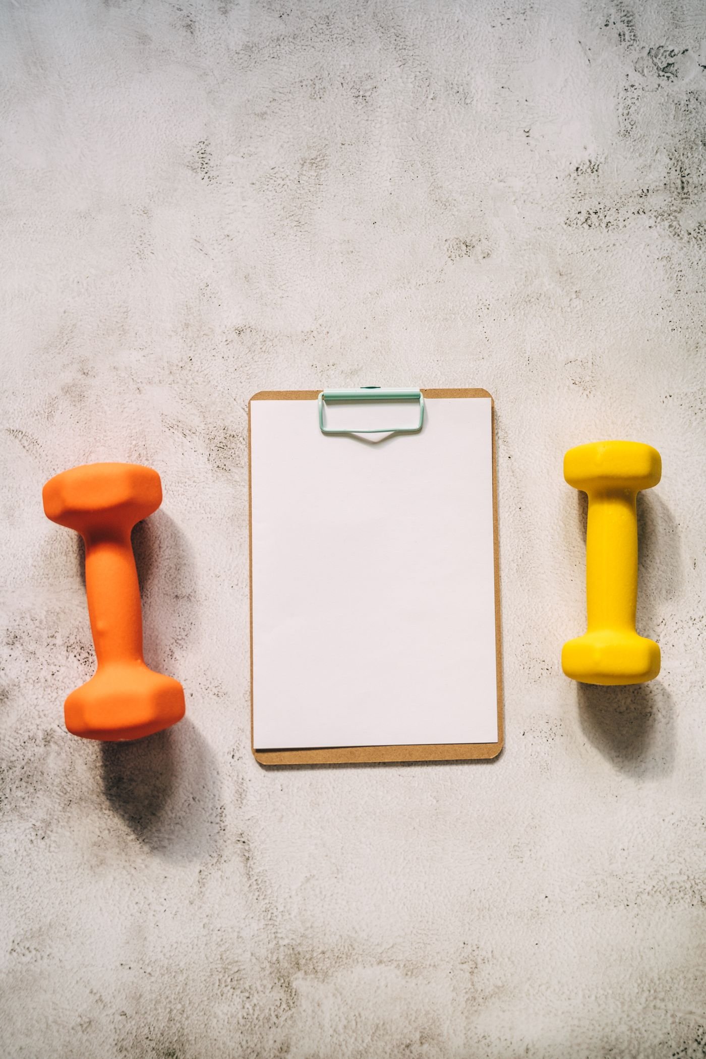 Workout clipboard and dumbbells arranged for training planning