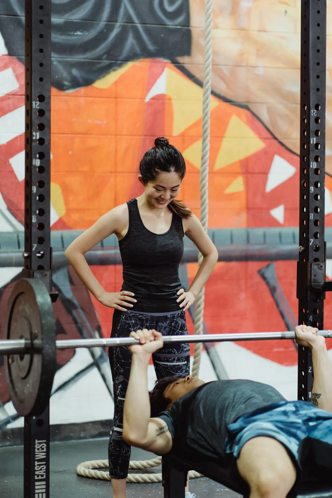 Man pressing a barbell with a spotter standing behind the bench