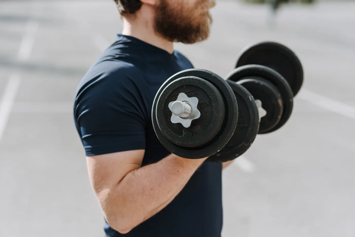 Man performing dumbbell curls outdoors