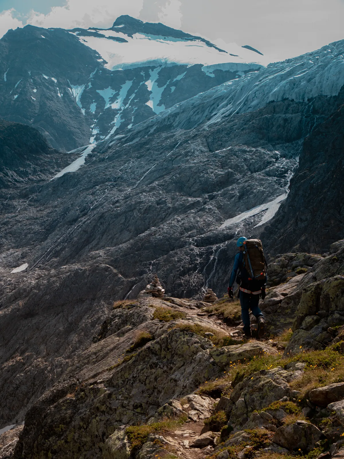 Hiker moving across an uneven rocky mountain trail