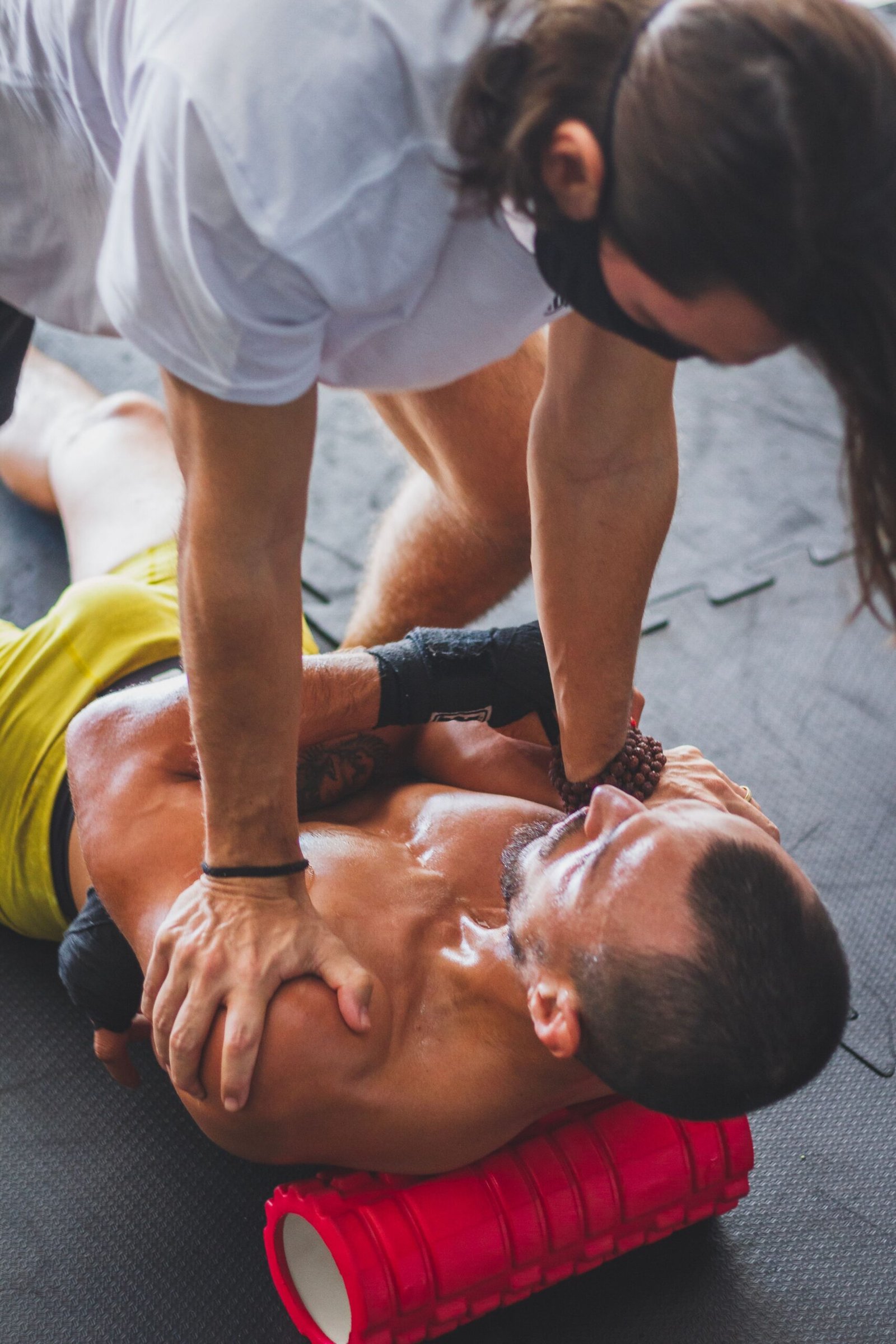 Trainer assisting a man with foam-roller recovery