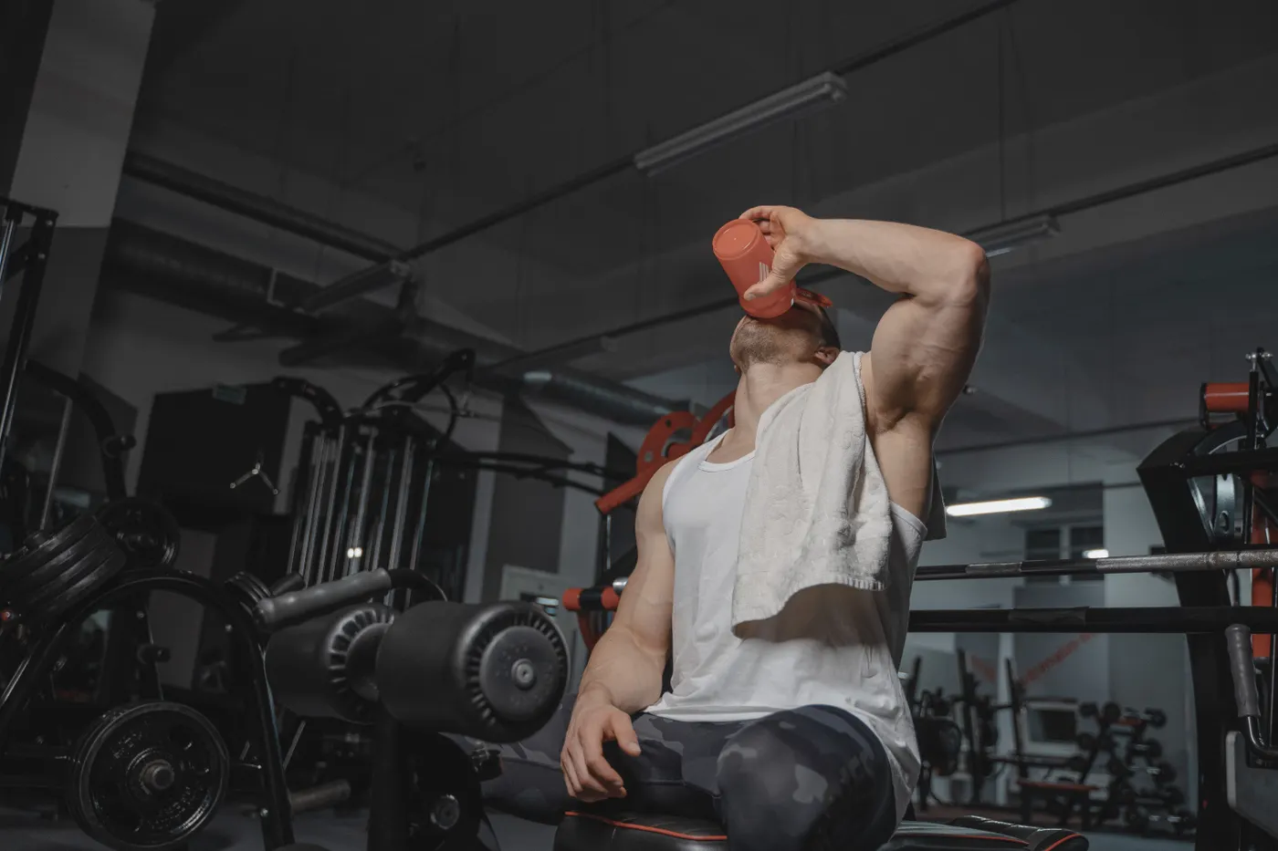 Muscular athlete drinking from a shaker during a break in the gym