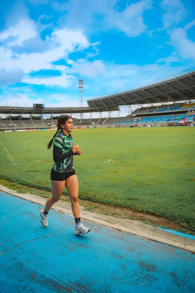 Runner moving steadily along a blue stadium track