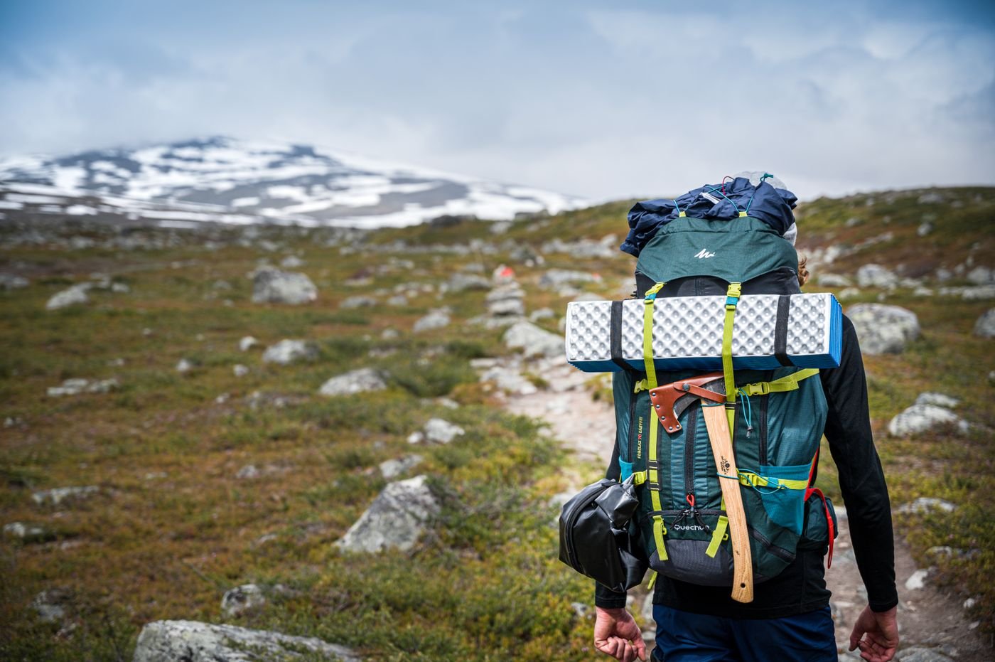 Backpacker hiking uphill on an uneven rocky trail
