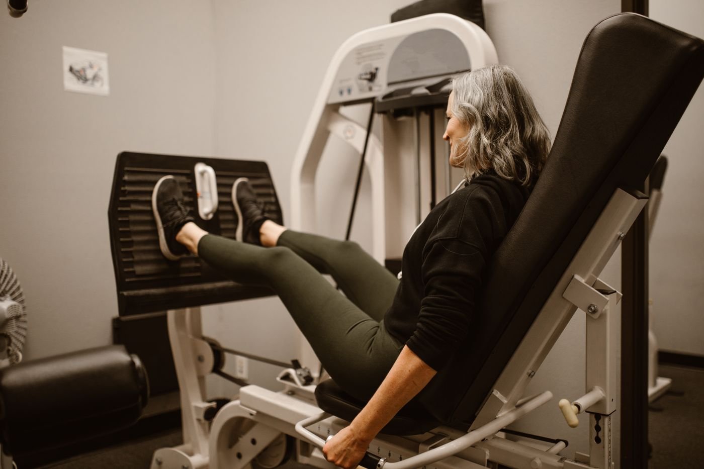 Mature woman training on a leg press machine at the gym