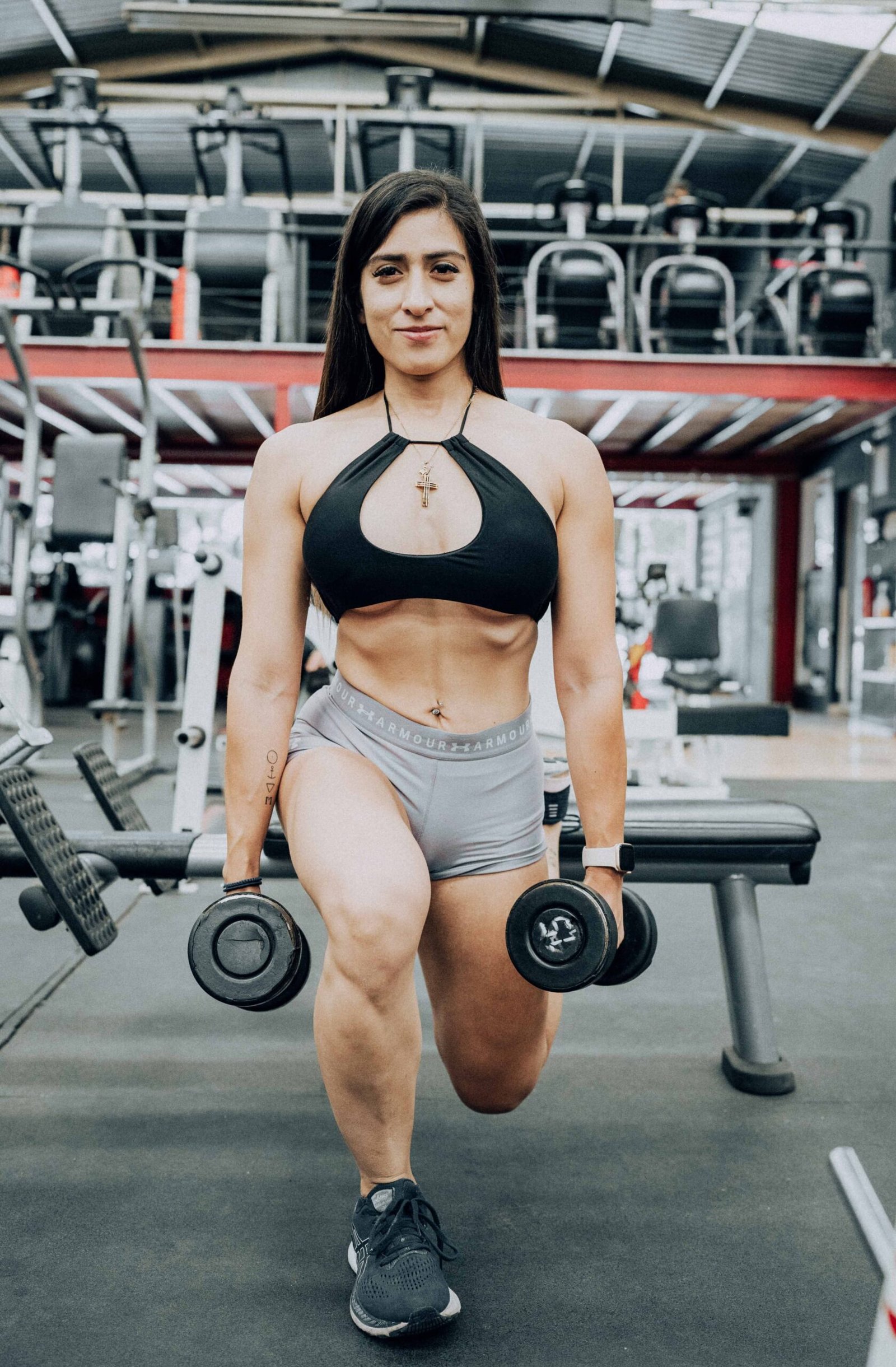 Athlete doing a dumbbell lunge with weights held at her sides