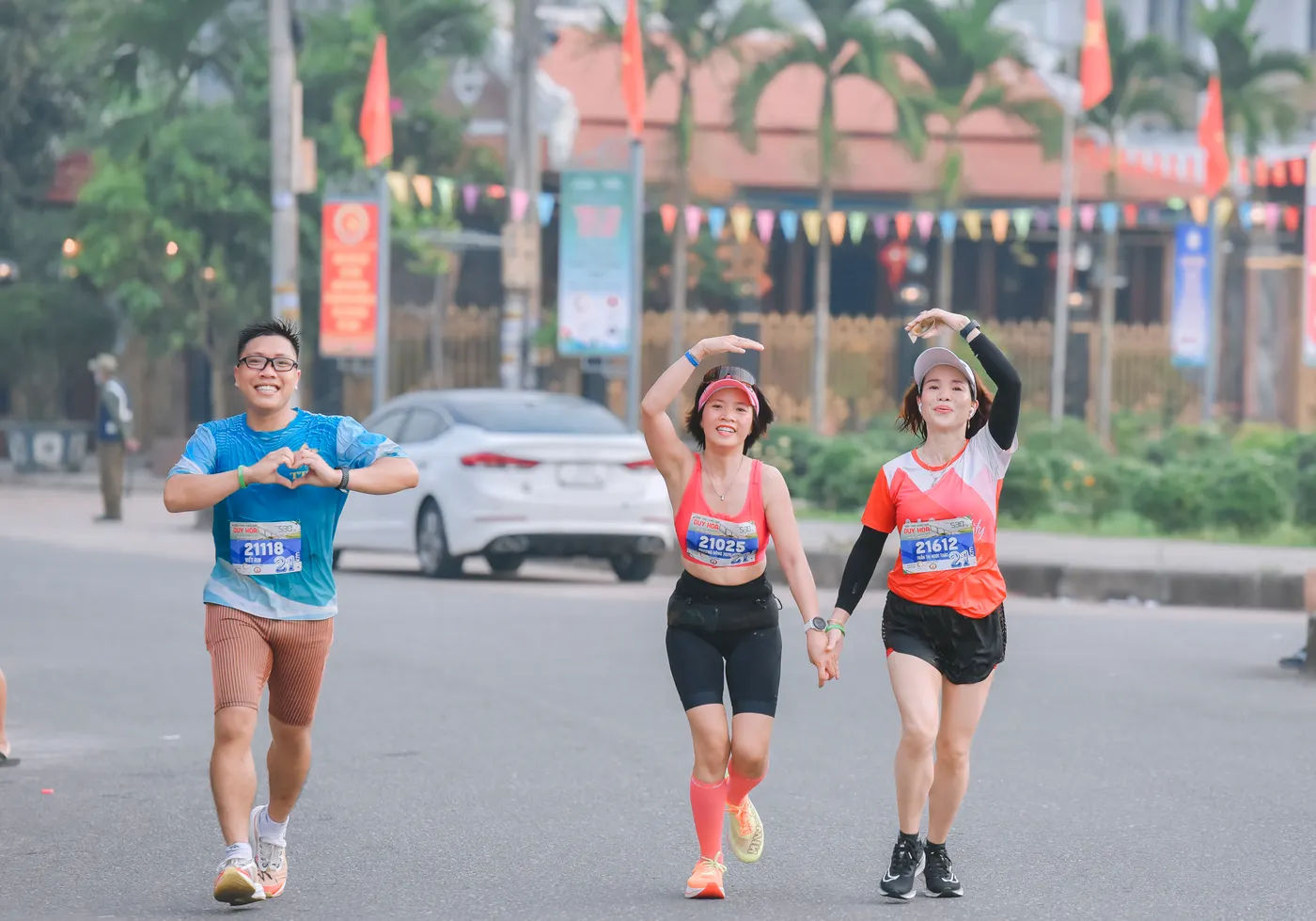 Three runners smiling together during a community marathon