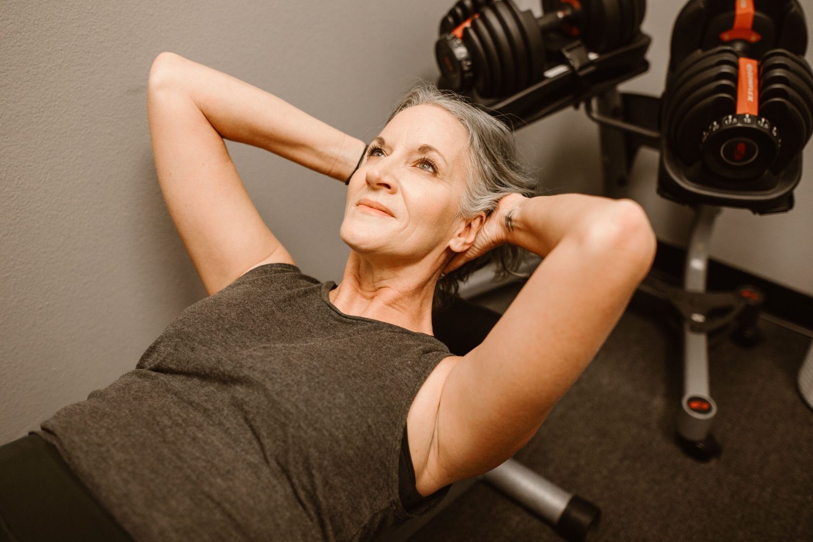 Older woman performing dumbbell resistance training in a fitness center