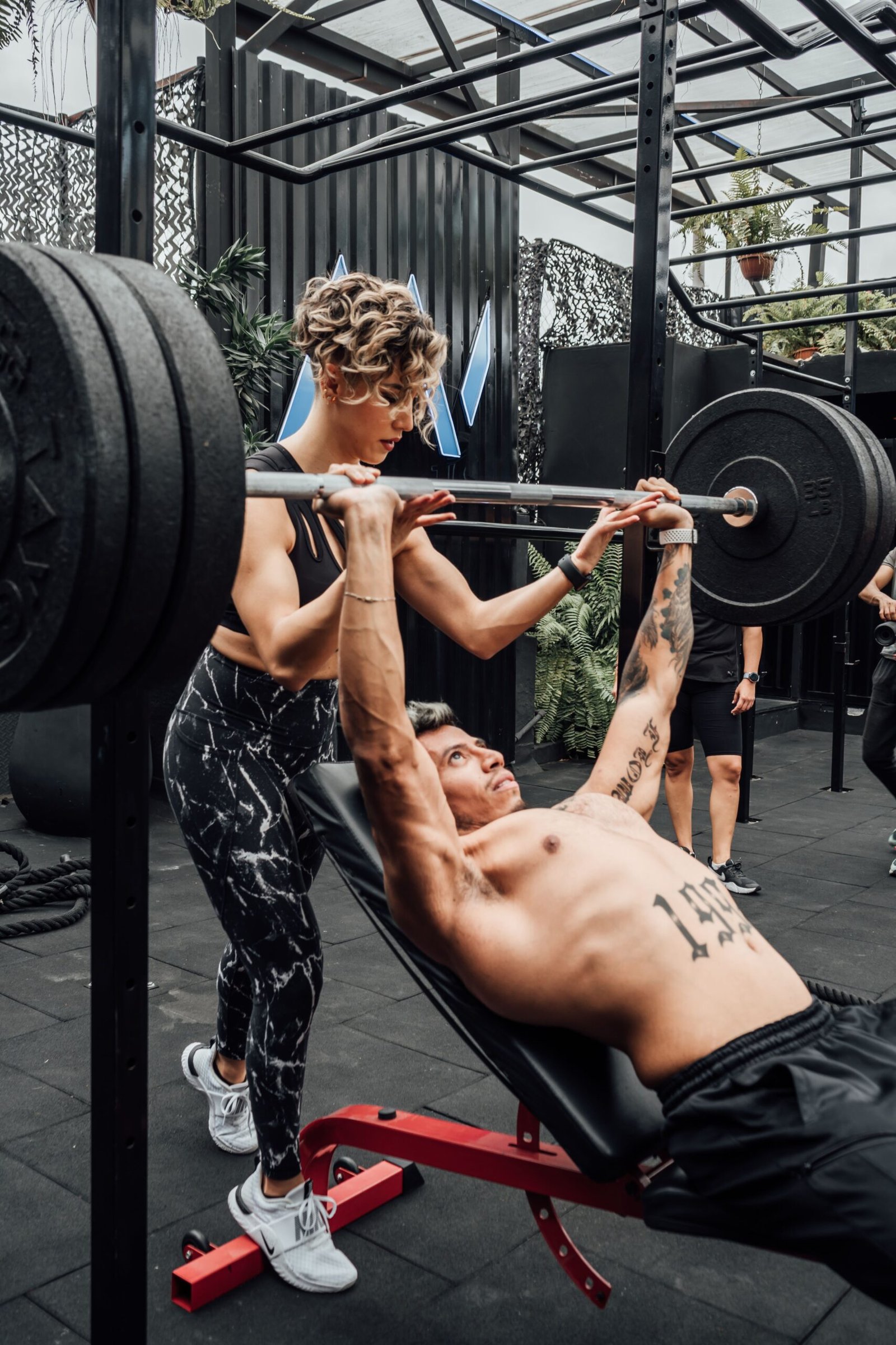 Man bench pressing with a spotter