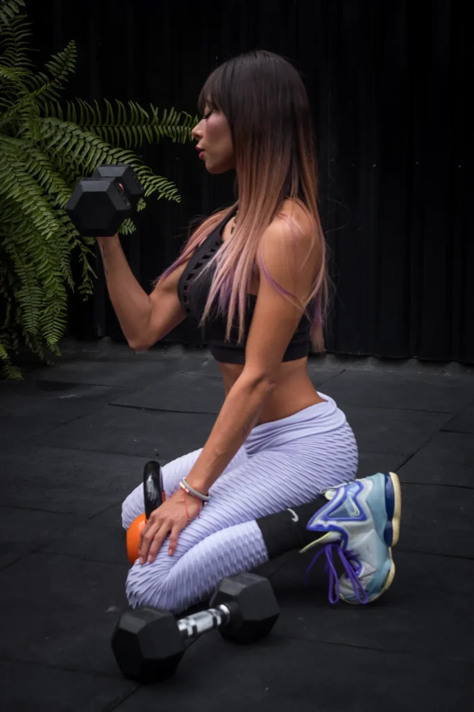 Woman kneeling and lifting a dumbbell during an indoor strength workout