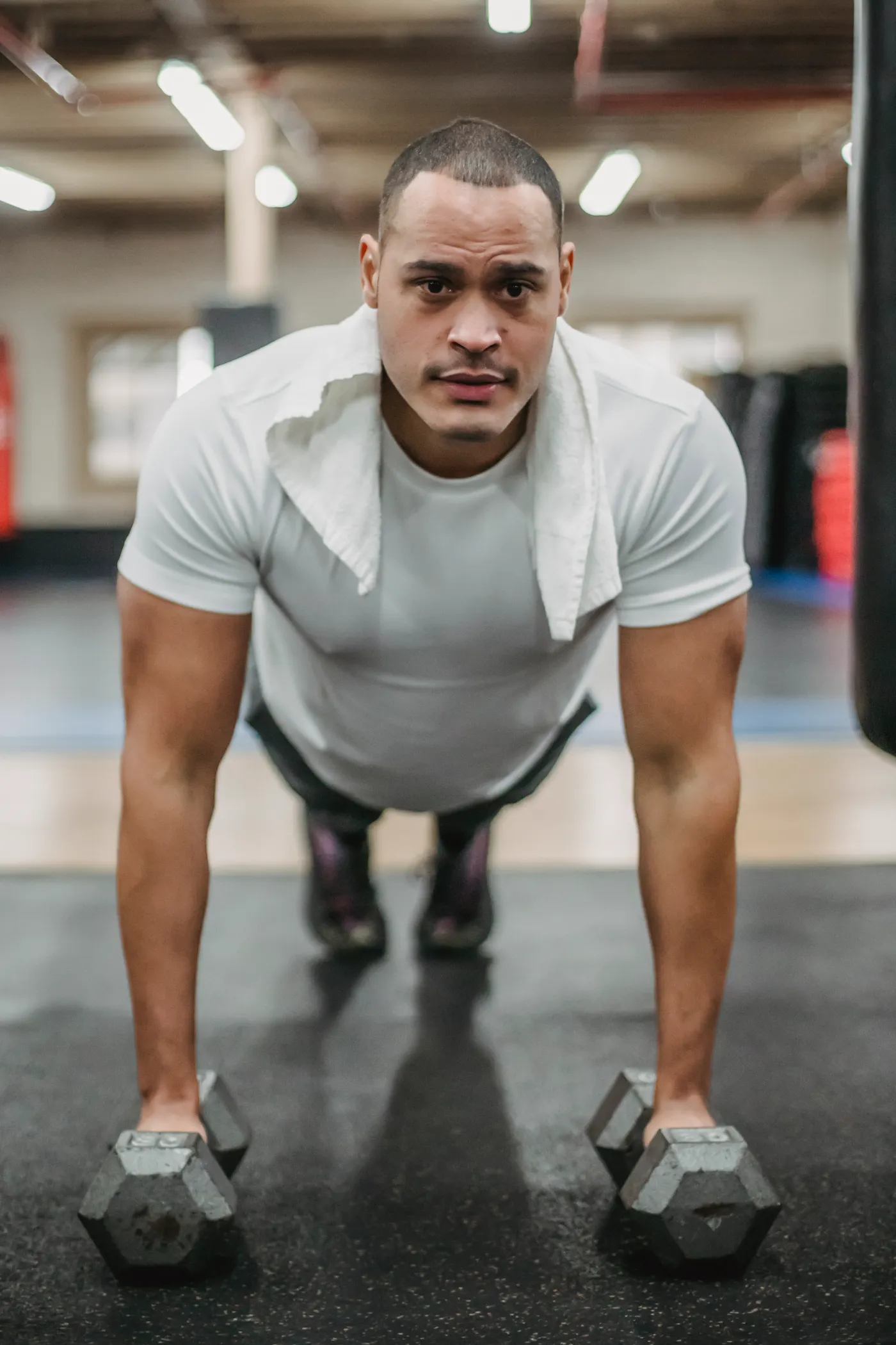 Athlete performing controlled push-ups on dumbbells in a gym