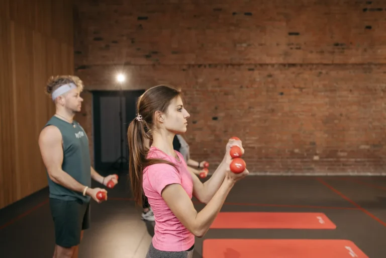 Adults exercising with dumbbells together in a gym