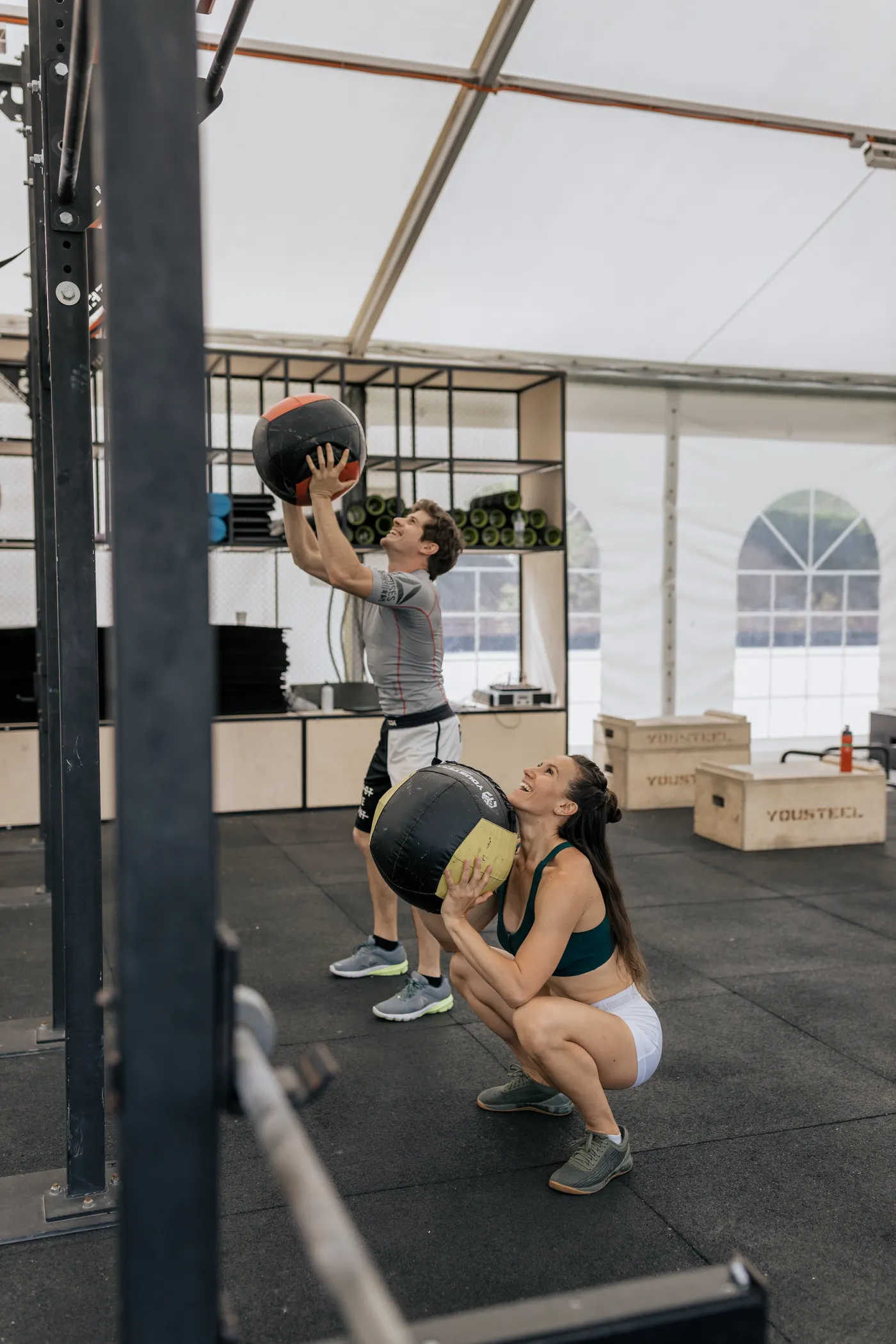 Two athletes practicing medicine-ball movements in a gym