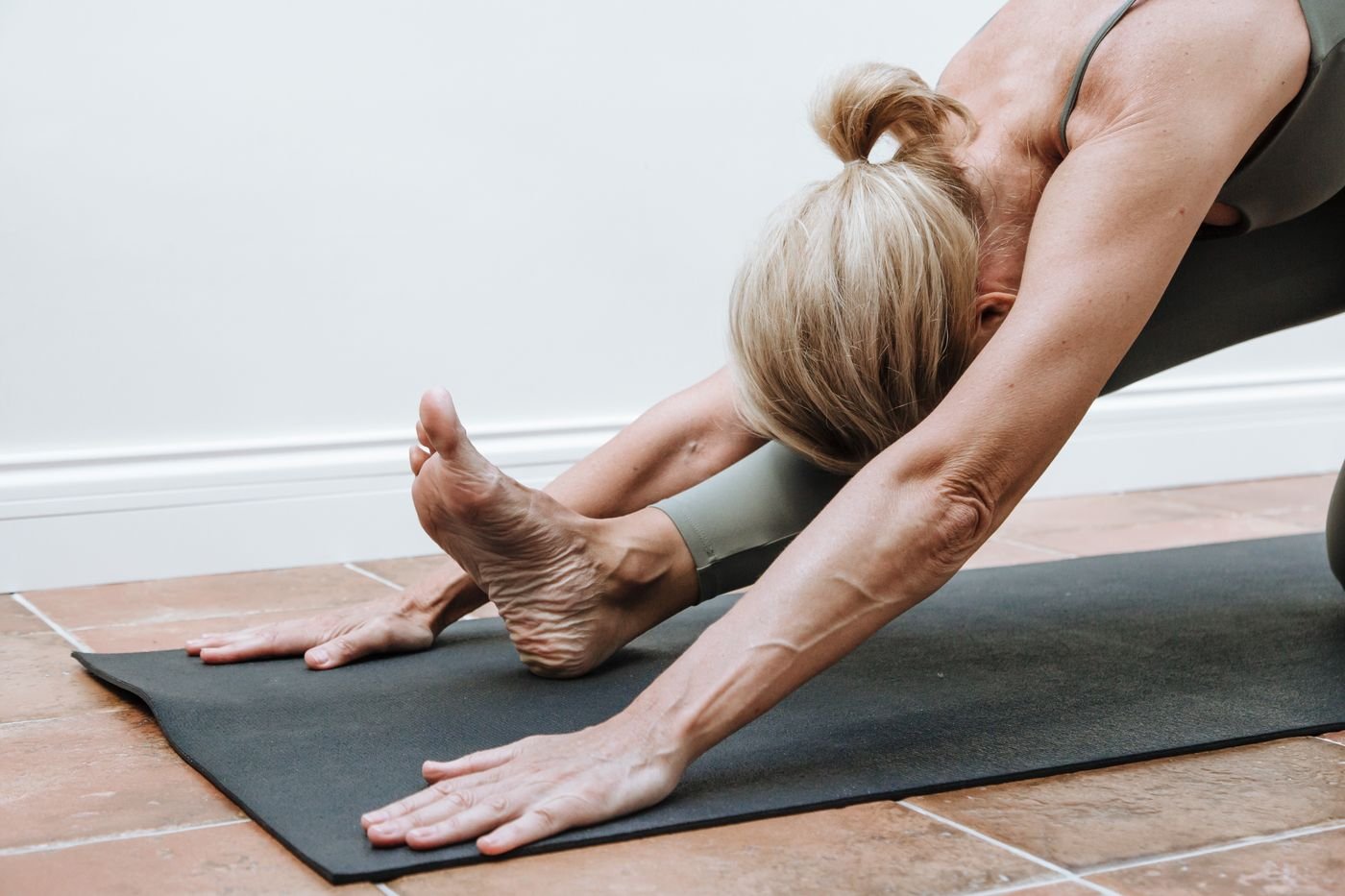 Woman performing a controlled floor stretch on a mat