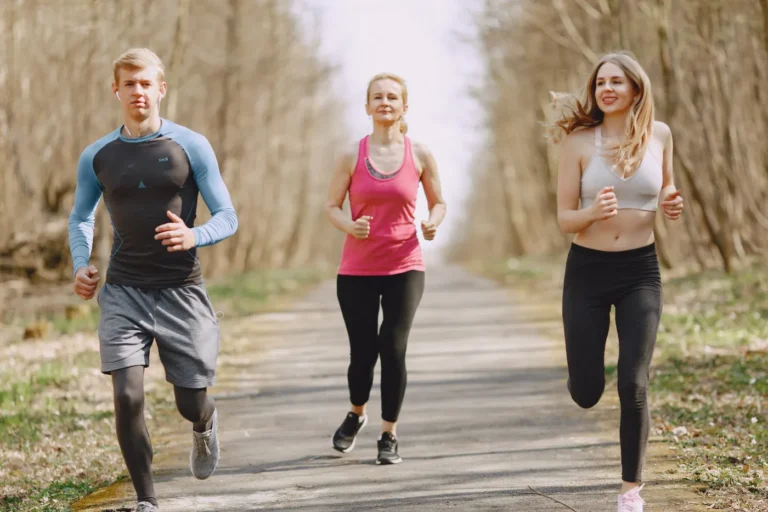 Three adults jogging together on a leafy park path
