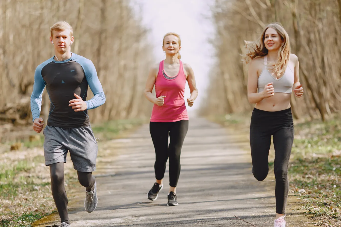 Three adults jogging together on a leafy park path