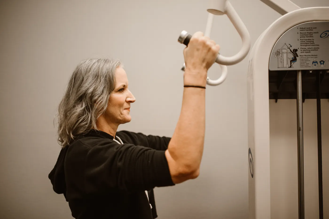 Senior woman using strength-training equipment in a gym