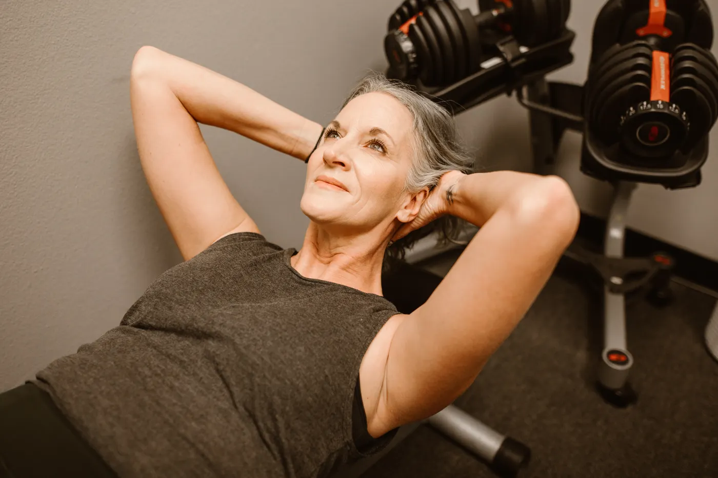 Senior woman strengthening her arms with dumbbells in a fitness center
