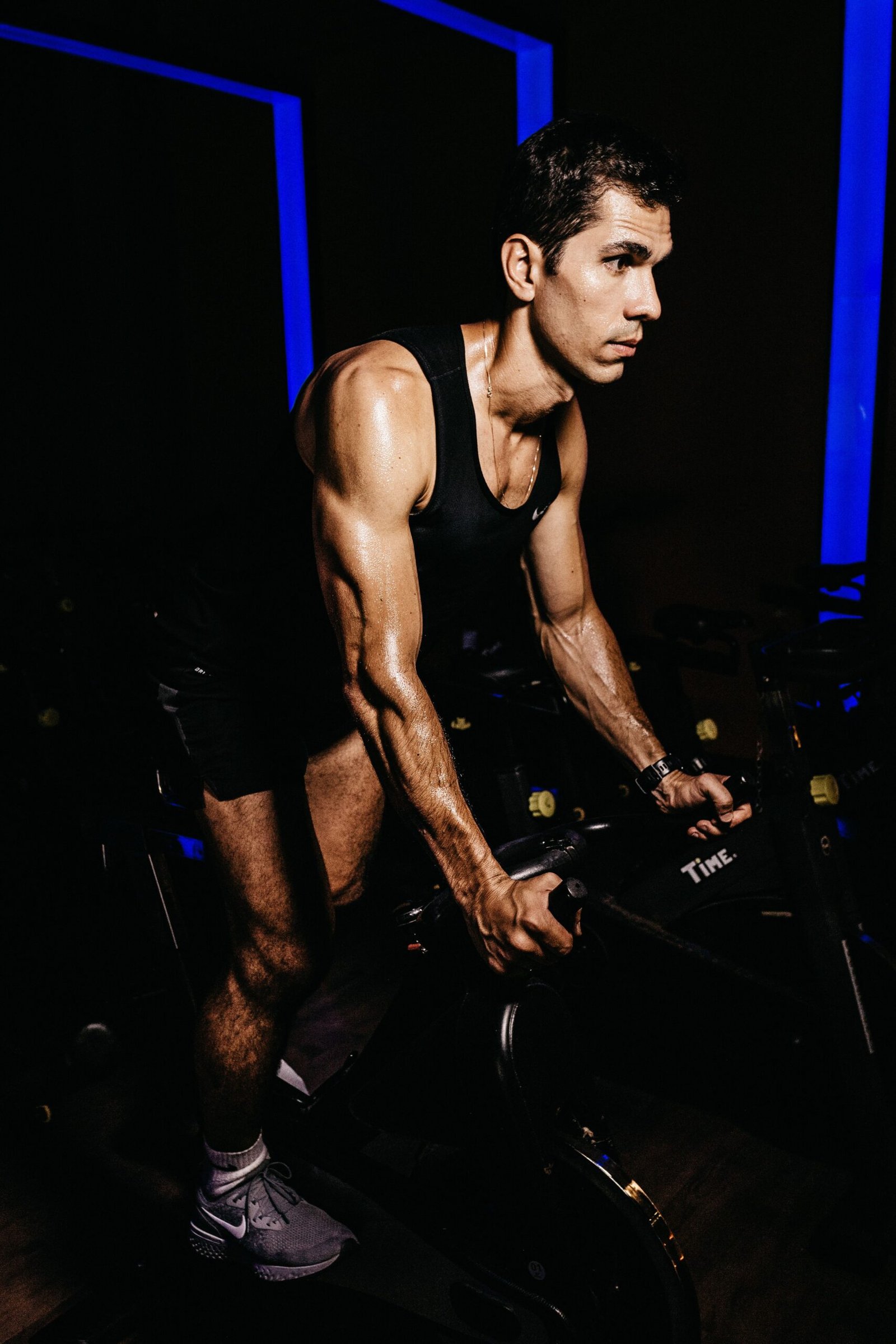Cyclist training on a stationary bike in a dark gym