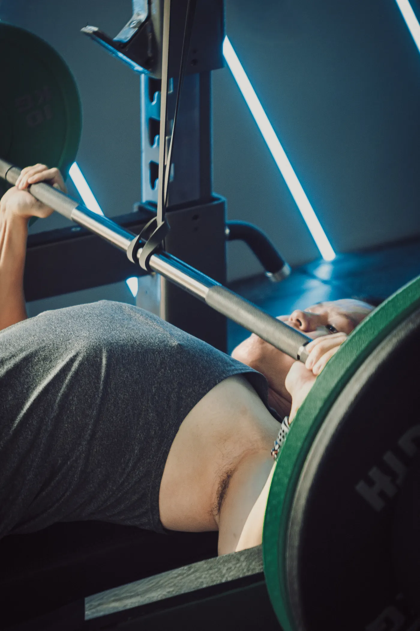 Man bench pressing in a gym with a weight bench and barbell
