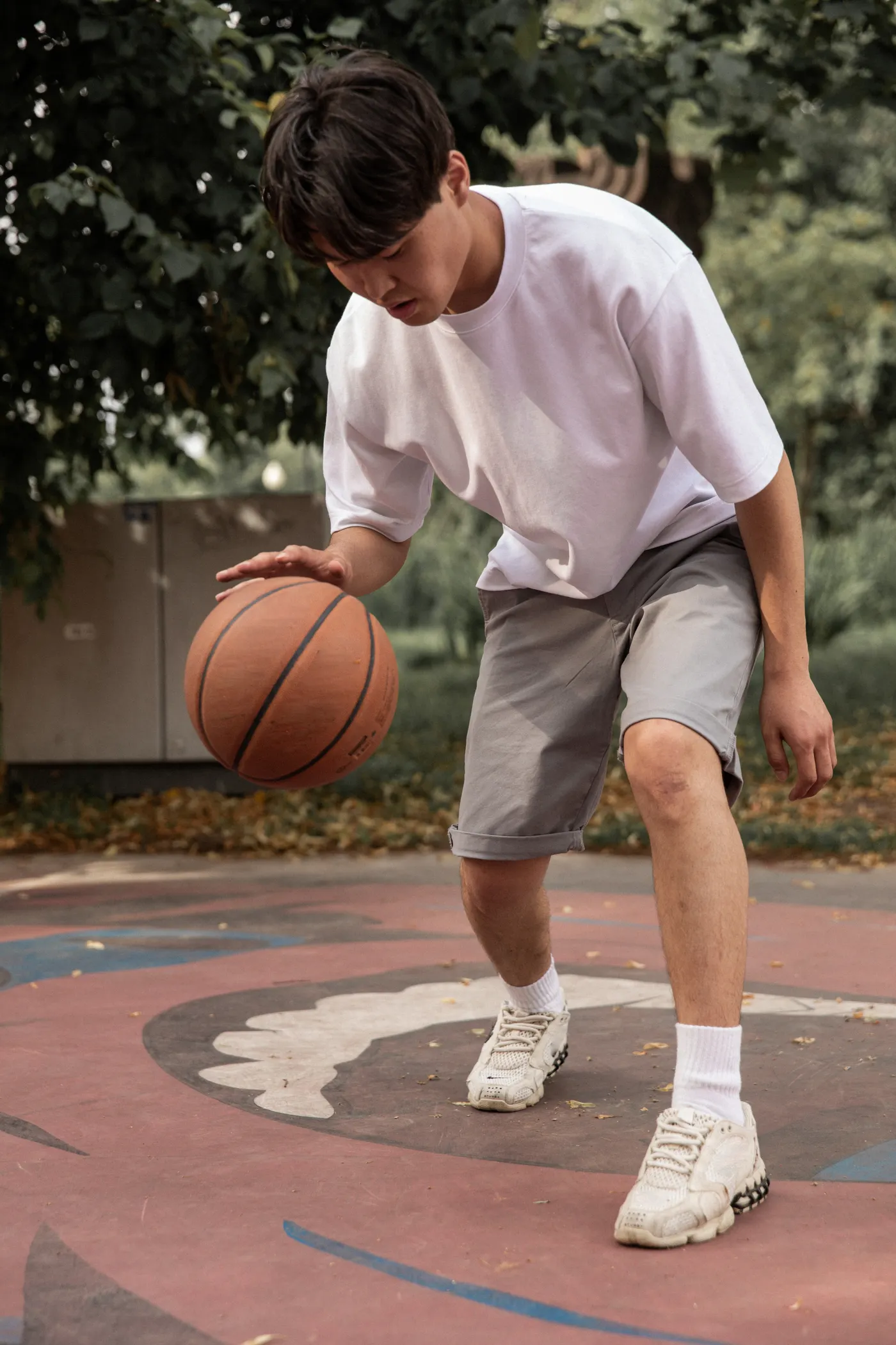 Basketball player practicing ball handling on an outdoor court
